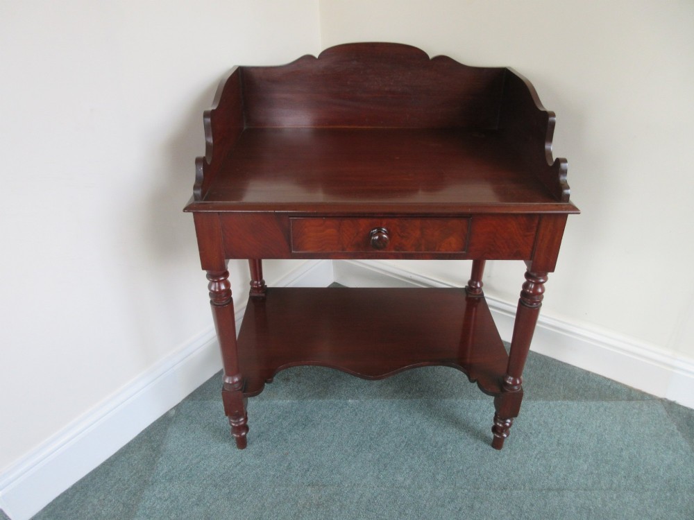 A Victorian mahogany night stand featuring a shaped gallery splashback, a single frieze drawer with a wooden knob, an open lower undertier, and turned legs. View VI
