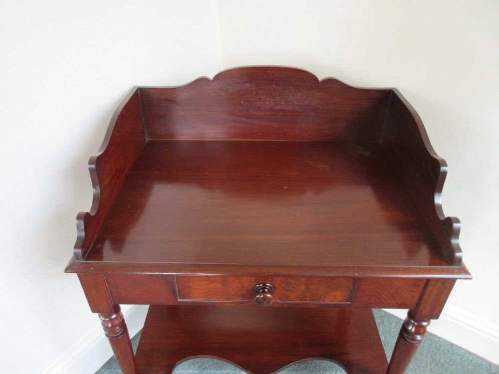 A Victorian mahogany night stand featuring a shaped gallery splashback, a single frieze drawer with a wooden knob, an open lower undertier, and turned legs. View VII
