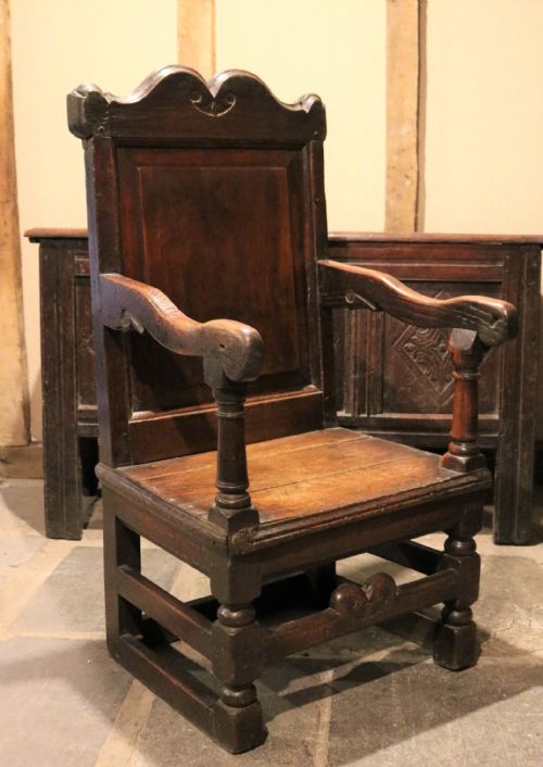 fig 1. A 17th-century Welsh oak armchair featuring a central yew-wood back panel, down-swept armrests, turned front legs, and a carved crest rail.