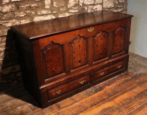 fig 1. An 18th-century dark oak Welsh coffer featuring four arched inlaid panels above two drawers with brass handles.