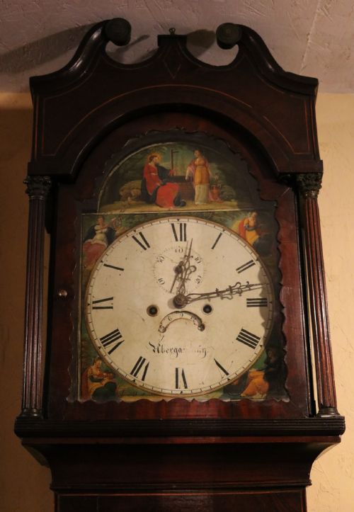 fig 2. A tall 19th-century Welsh mahogany longcase clock featuring a swan-neck pediment hood, painted arch dial with Roman numerals, and flame mahogany trunk door.