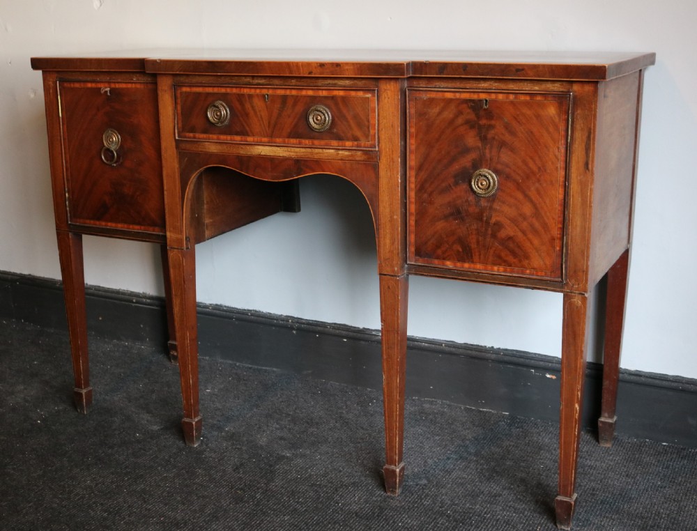 A late 18th-century Sheraton-style mahogany sideboard featuring flame veneer cupboards, a central drawer, an arched apron, and slender tapered legs. View III