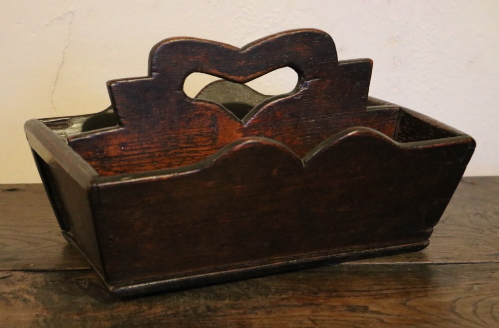 A dark oak 18th-century cutlery tray featuring a central divider with a carved heart-shaped handle aperture and scalloped sides. View III