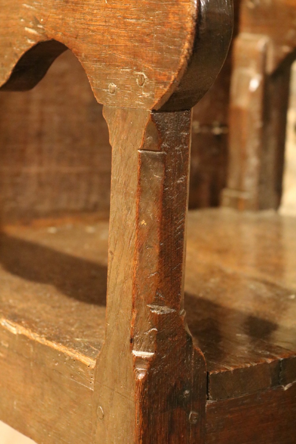 A 17th-century Welsh dark oak chair-table shown with its rectangular wooden top locked upright to form a backrest above shaped armrests and a square seat. View III