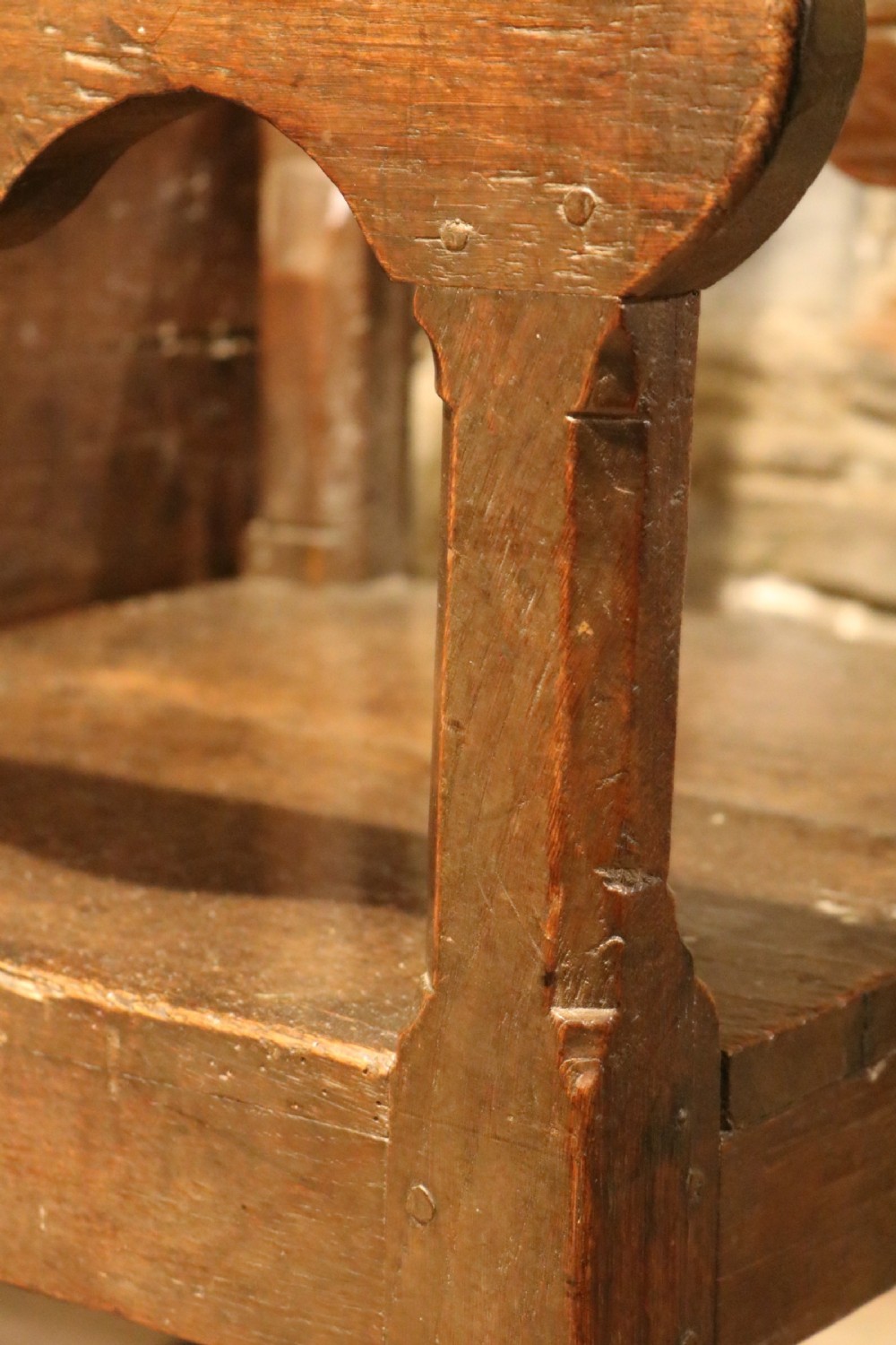 A 17th-century Welsh dark oak chair-table shown with its rectangular wooden top locked upright to form a backrest above shaped armrests and a square seat. View V