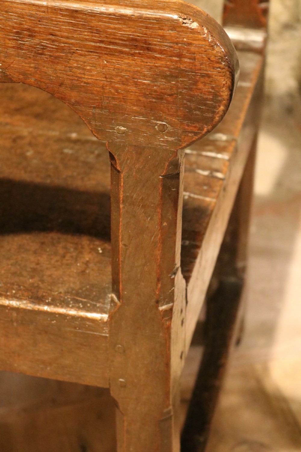 A 17th-century Welsh dark oak chair-table shown with its rectangular wooden top locked upright to form a backrest above shaped armrests and a square seat. View VI