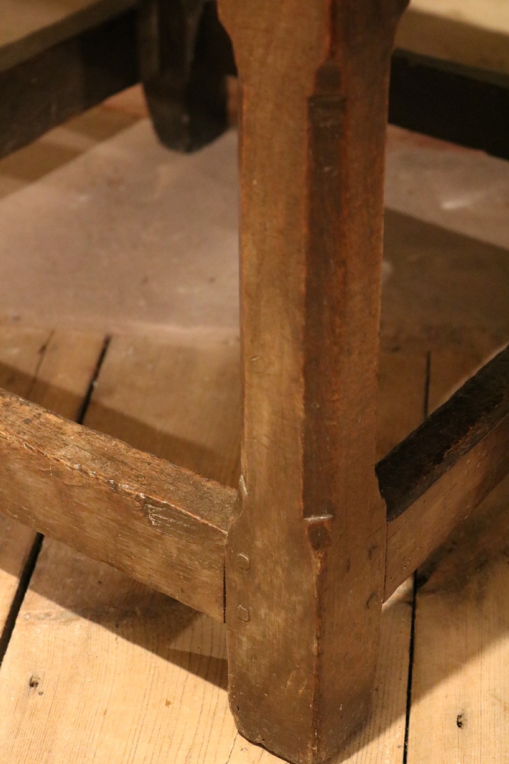 A 17th-century Welsh dark oak chair-table shown with its rectangular wooden top locked upright to form a backrest above shaped armrests and a square seat. View VII