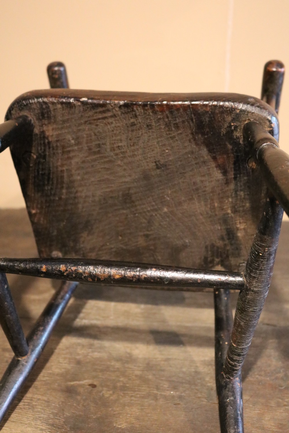 A nineteenth-century dark-stained Welsh childs primitive Windsor armchair featuring a thick slab seat, turned arms, and splayed legs. View VIII