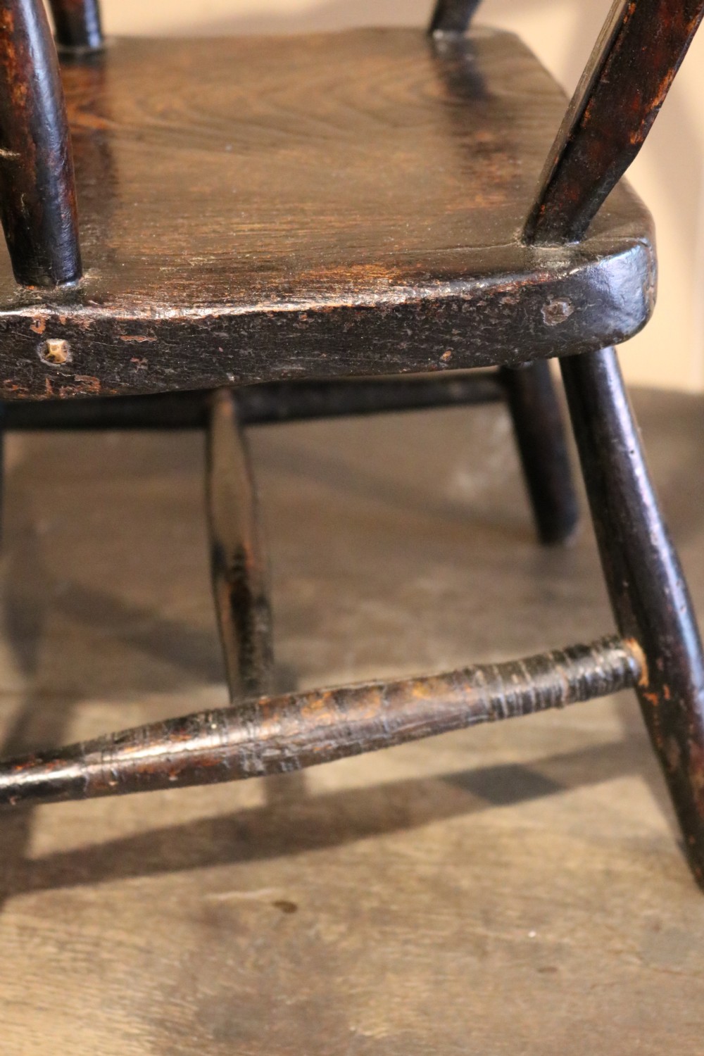 A nineteenth-century dark-stained Welsh childs primitive Windsor armchair featuring a thick slab seat, turned arms, and splayed legs. View IX