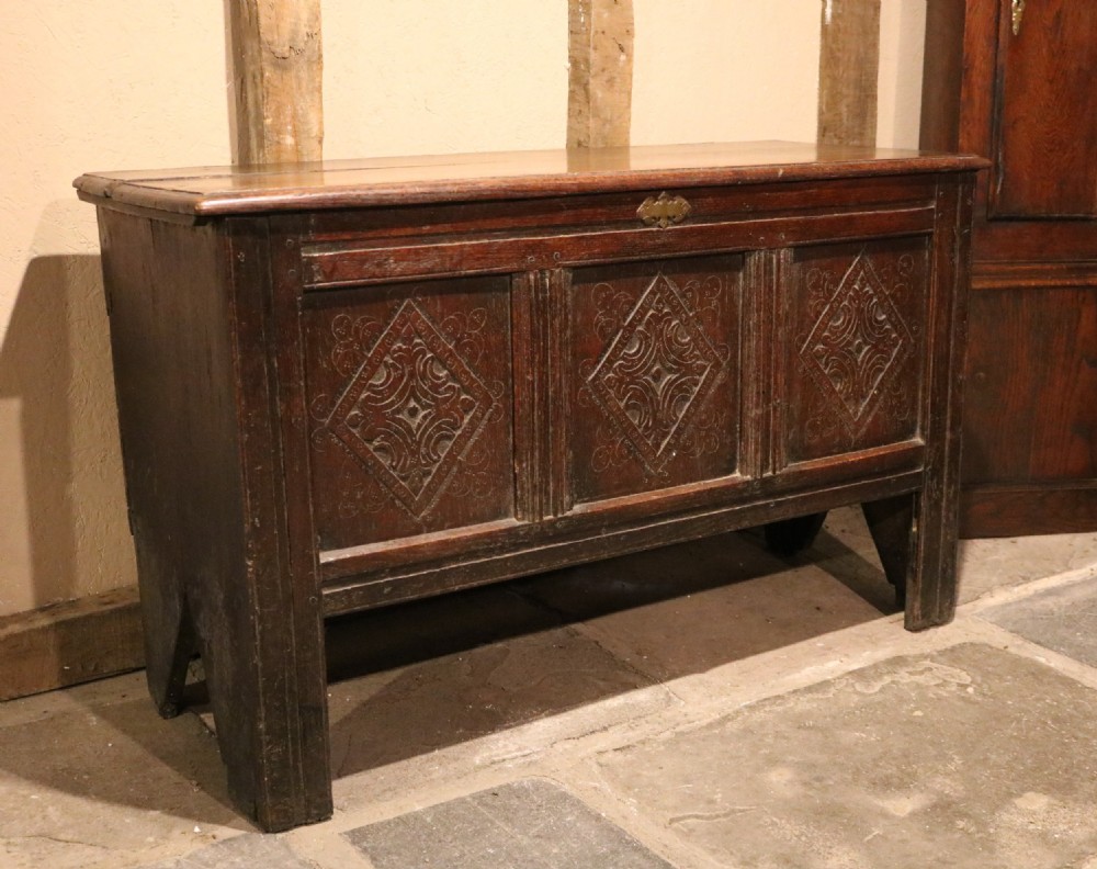 A seventeenth-century dark oak coffer featuring three carved front panels with geometric diamond lozenge motifs and a brass keyhole escutcheon. View II