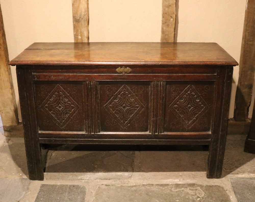A seventeenth-century dark oak coffer featuring three carved front panels with geometric diamond lozenge motifs and a brass keyhole escutcheon. View III