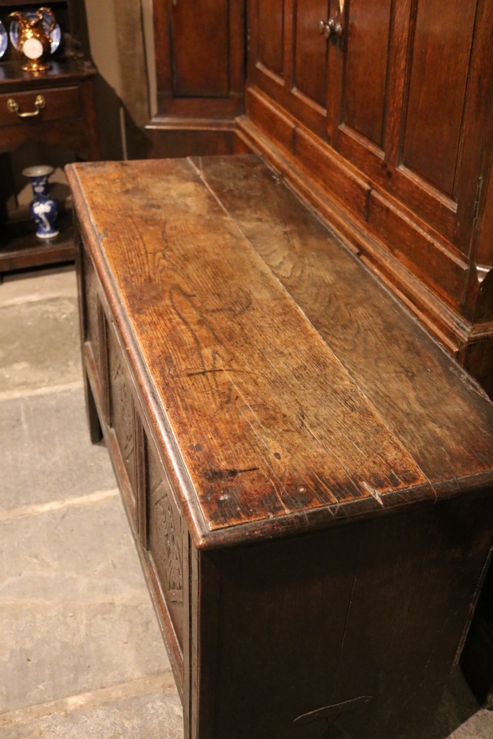 A seventeenth-century dark oak coffer featuring three carved front panels with geometric diamond lozenge motifs and a brass keyhole escutcheon. View XII