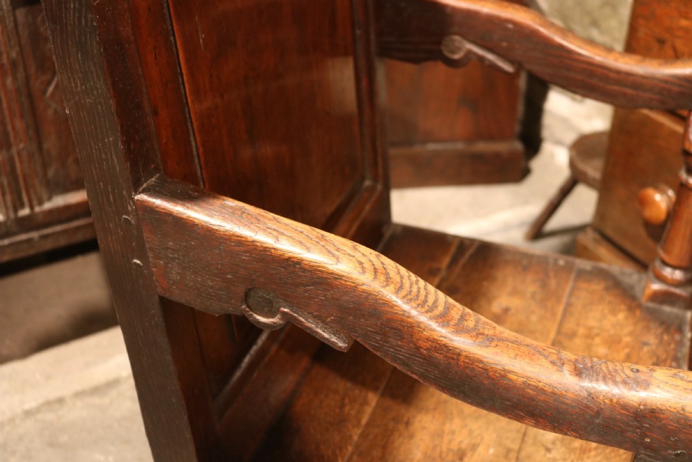 A 17th-century Welsh oak armchair featuring a central yew-wood back panel, down-swept armrests, turned front legs, and a carved crest rail. View IX