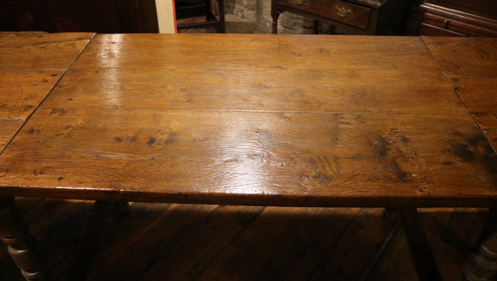 A long Basque chestnut extending dining table with a plank top, turned legs, and perimeter stretchers. View XIII