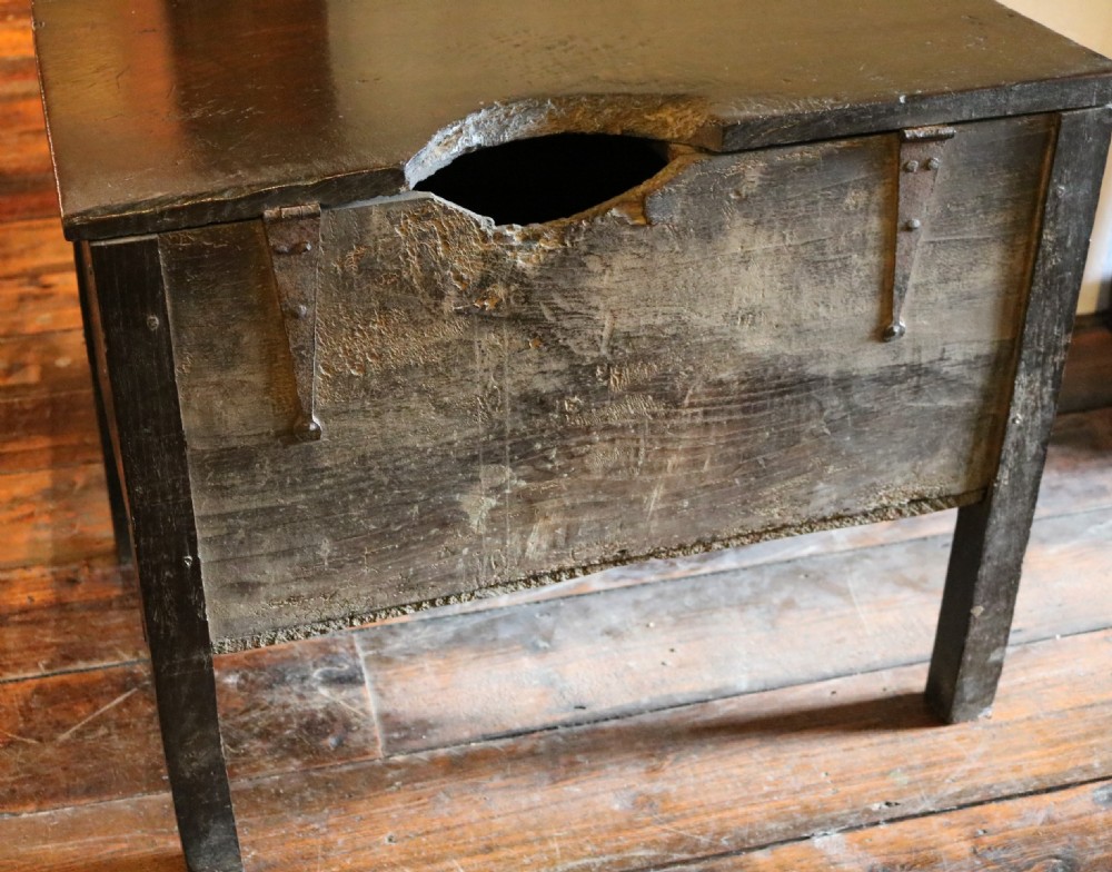 A dark brown primitive oak coffer featuring a hinged lid, straight legs, and a small central iron keyhole. View VII