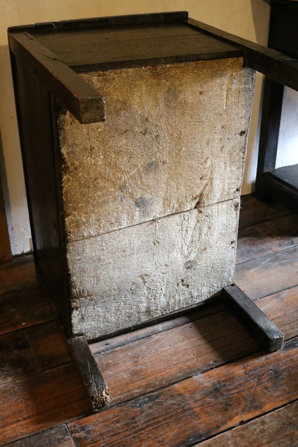 A dark brown primitive oak coffer featuring a hinged lid, straight legs, and a small central iron keyhole. View VIII