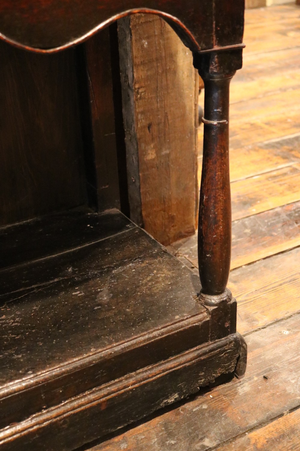 An 18th-century dark oak Welsh dresser featuring an upper plate rack, three brass-handled drawers over a scalloped apron, and a lower potboard shelf. View XIV