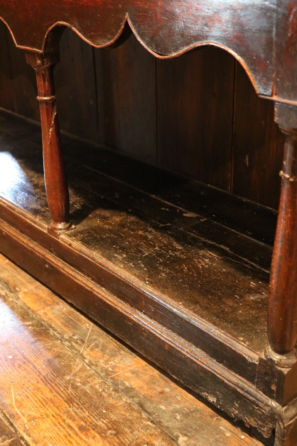An 18th-century dark oak Welsh dresser featuring an upper plate rack, three brass-handled drawers over a scalloped apron, and a lower potboard shelf. View XVIII