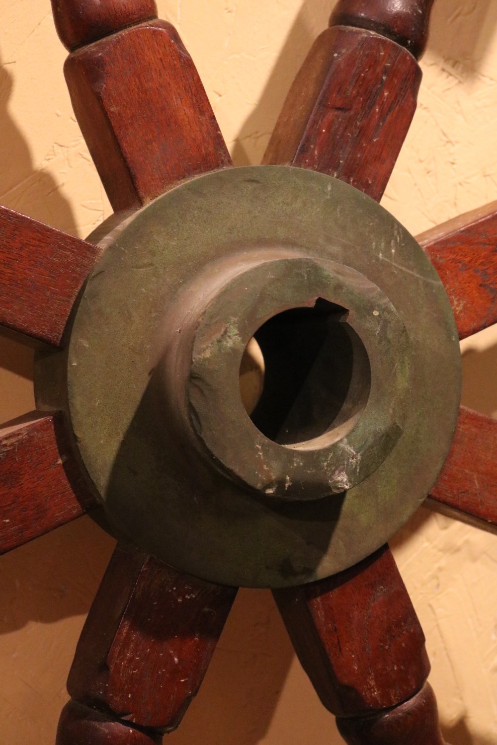 A Victorian wooden ships wheel featuring eight turned spokes, a central brass boss, and outer brass rim reinforcement. View VI