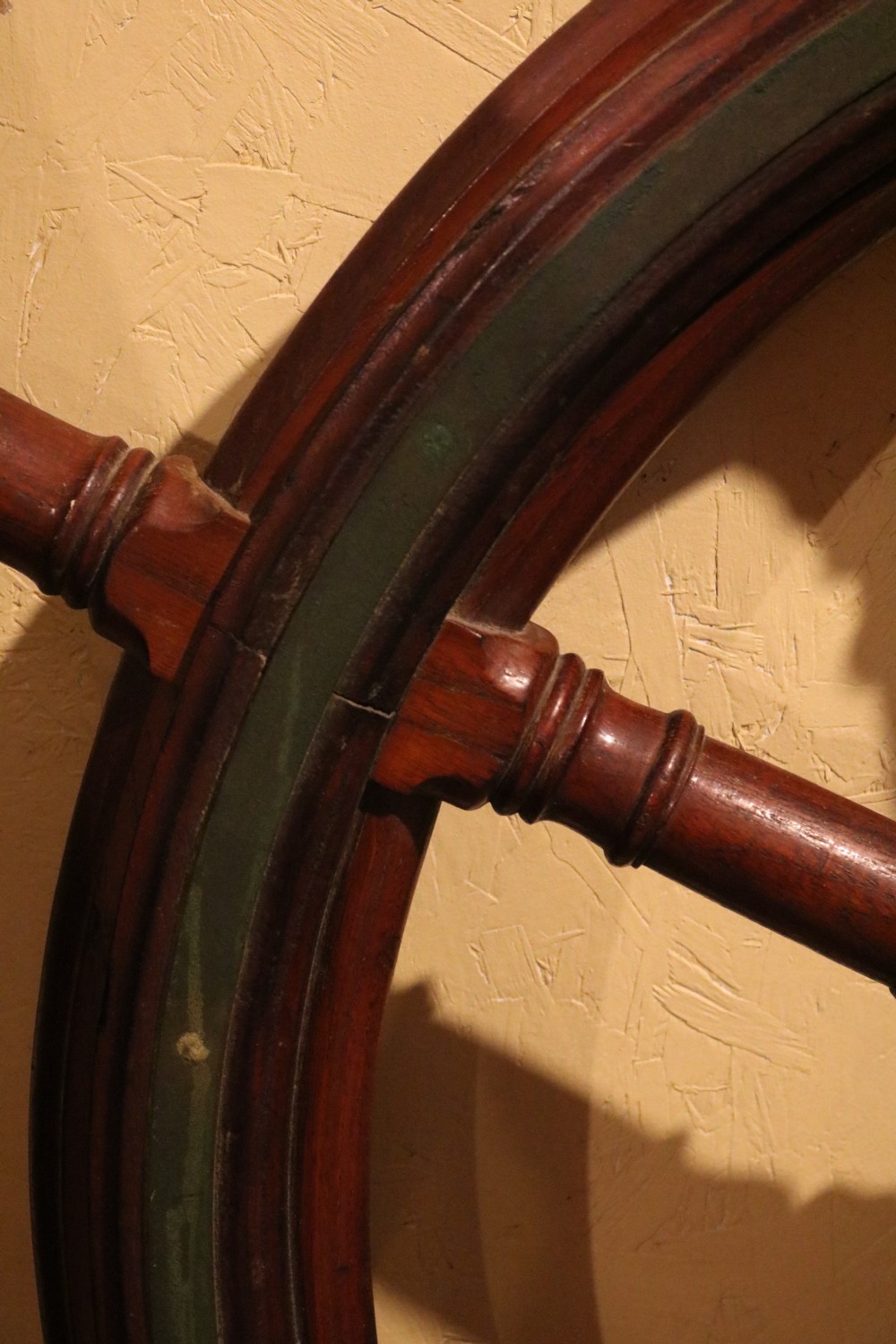 A Victorian wooden ships wheel featuring eight turned spokes, a central brass boss, and outer brass rim reinforcement. View VII