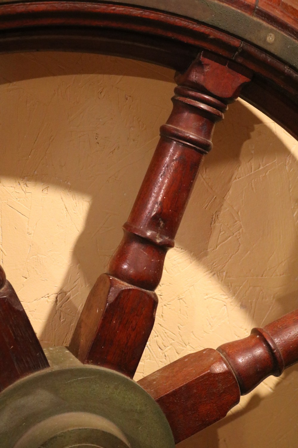 A Victorian wooden ships wheel featuring eight turned spokes, a central brass boss, and outer brass rim reinforcement. View VIII