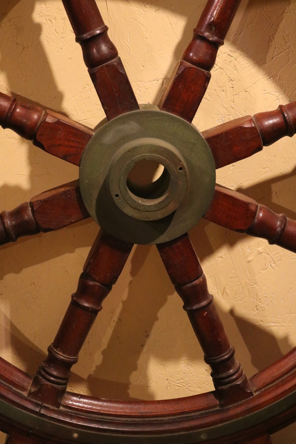 A Victorian wooden ships wheel featuring eight turned spokes, a central brass boss, and outer brass rim reinforcement. View XI