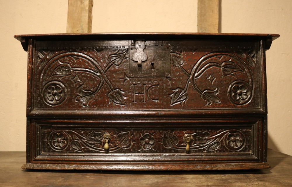 A 17th-century dark oak carved table box featuring scrollwork leaf motifs, carved initials HC, an iron lockplate, and a lower drawer. View II
