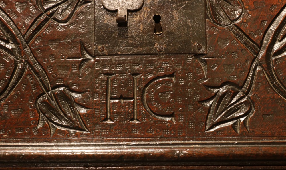 A 17th-century dark oak carved table box featuring scrollwork leaf motifs, carved initials HC, an iron lockplate, and a lower drawer. View III