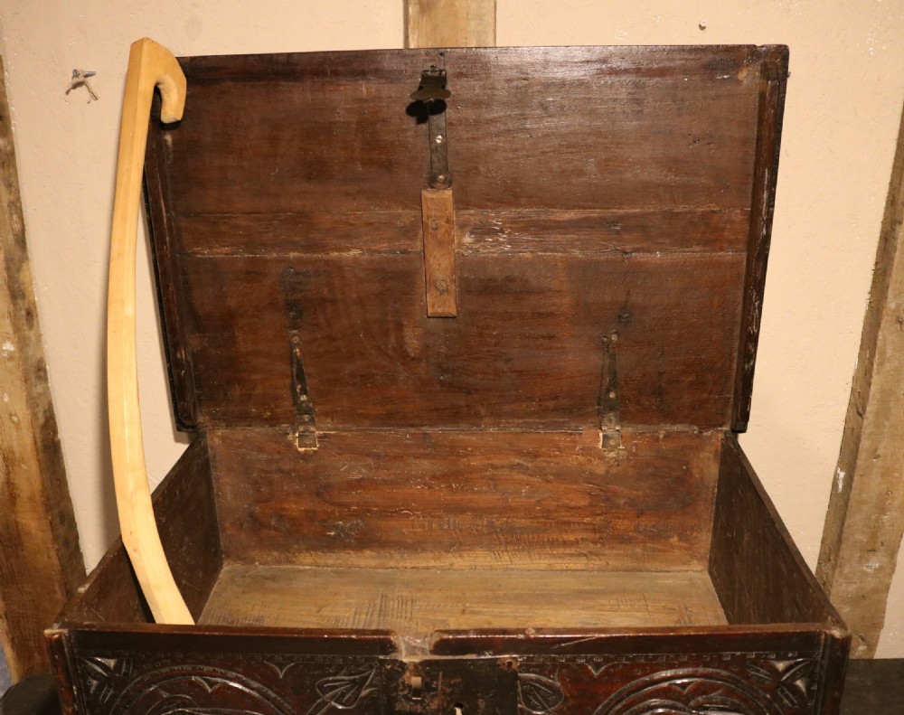A 17th-century dark oak carved table box featuring scrollwork leaf motifs, carved initials HC, an iron lockplate, and a lower drawer. View XII