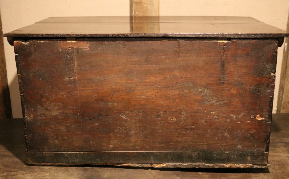 A 17th-century dark oak carved table box featuring scrollwork leaf motifs, carved initials HC, an iron lockplate, and a lower drawer. View XVII