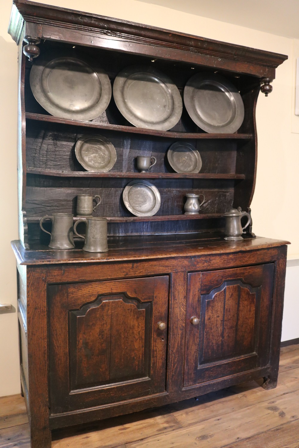 A dark oak Welsh cupboard dresser with a three-tiered upper display rack and a lower base containing two fielded panel doors. View III
