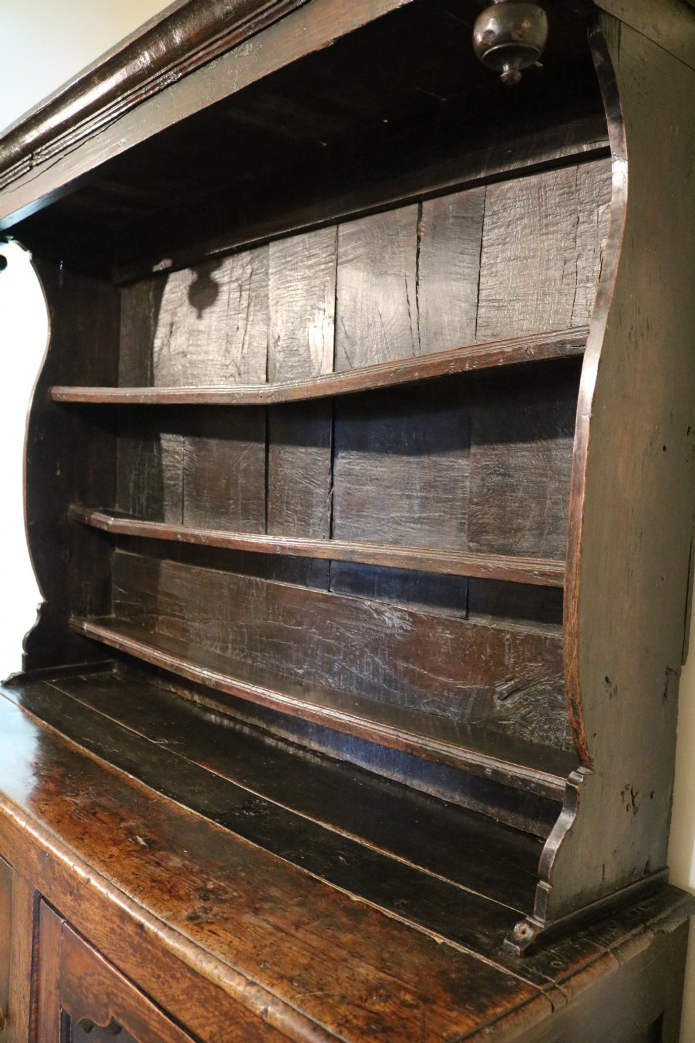 A dark oak Welsh cupboard dresser with a three-tiered upper display rack and a lower base containing two fielded panel doors. View X