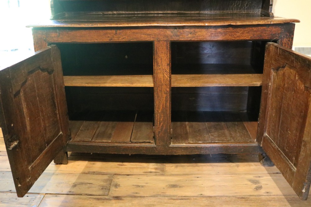 A dark oak Welsh cupboard dresser with a three-tiered upper display rack and a lower base containing two fielded panel doors. View XVIII