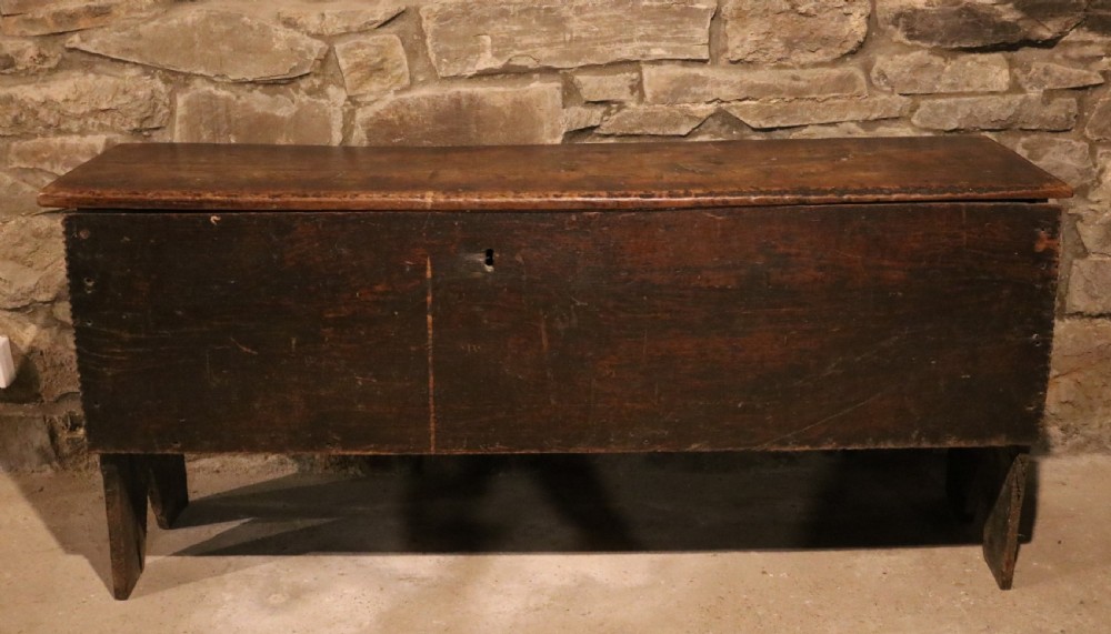 A dark brown 16th-century six-plank oak coffer featuring a rectangular top and V-cut end legs. View II