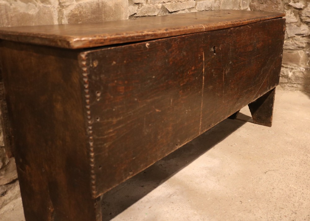 A dark brown 16th-century six-plank oak coffer featuring a rectangular top and V-cut end legs. View VI