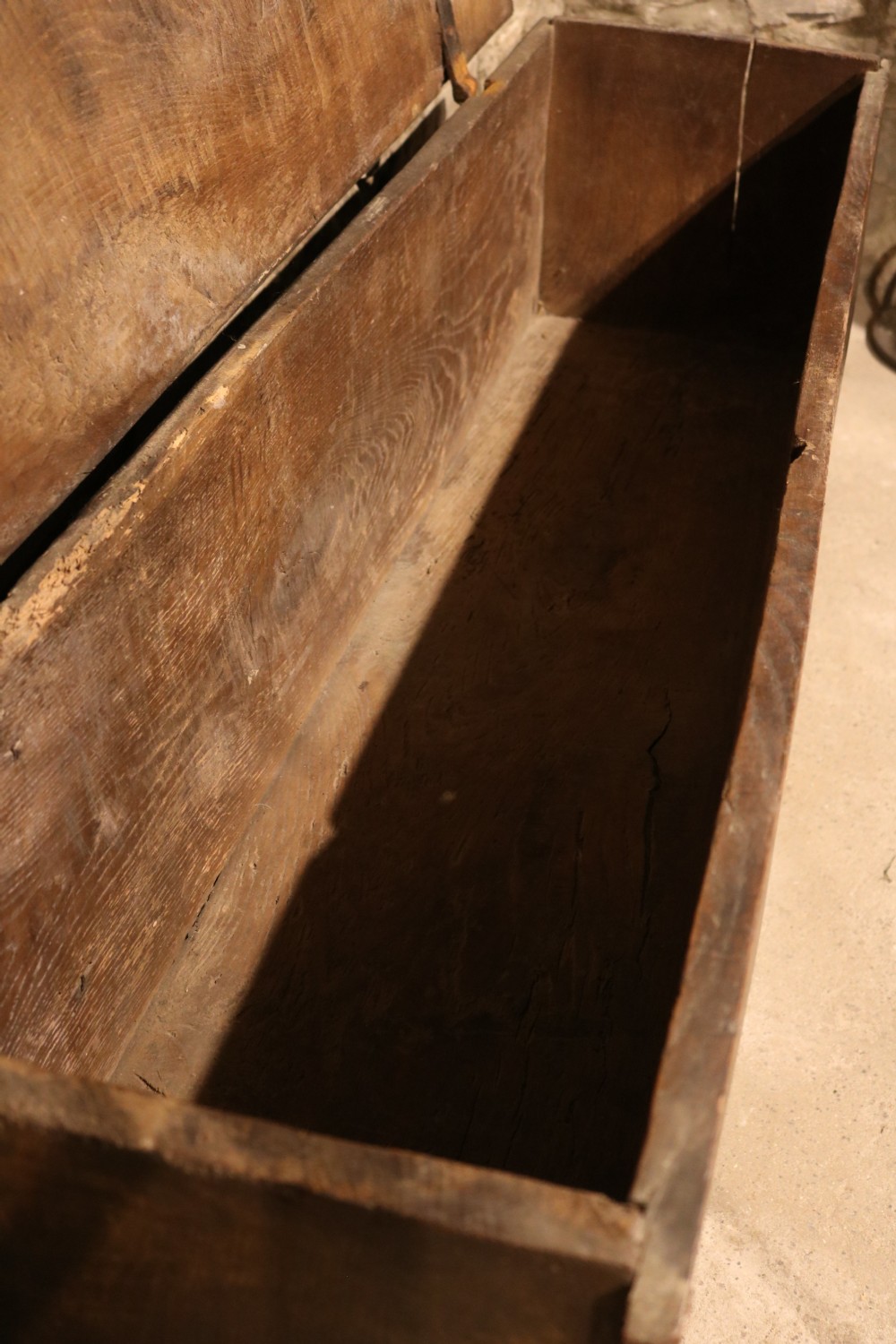 A dark brown 16th-century six-plank oak coffer featuring a rectangular top and V-cut end legs. View X