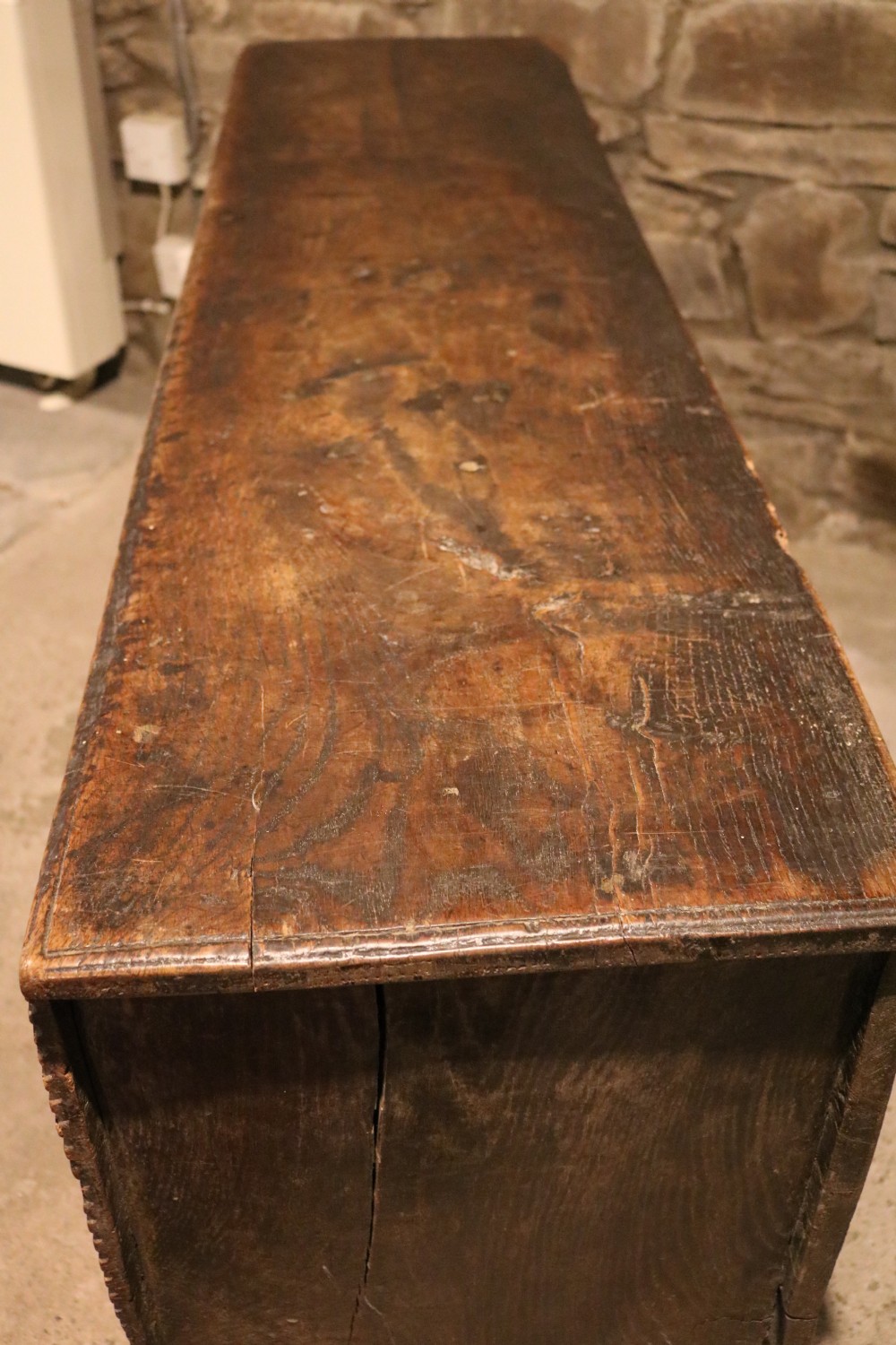 A dark brown 16th-century six-plank oak coffer featuring a rectangular top and V-cut end legs. View XI
