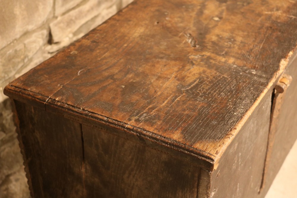 A dark brown 16th-century six-plank oak coffer featuring a rectangular top and V-cut end legs. View XVI