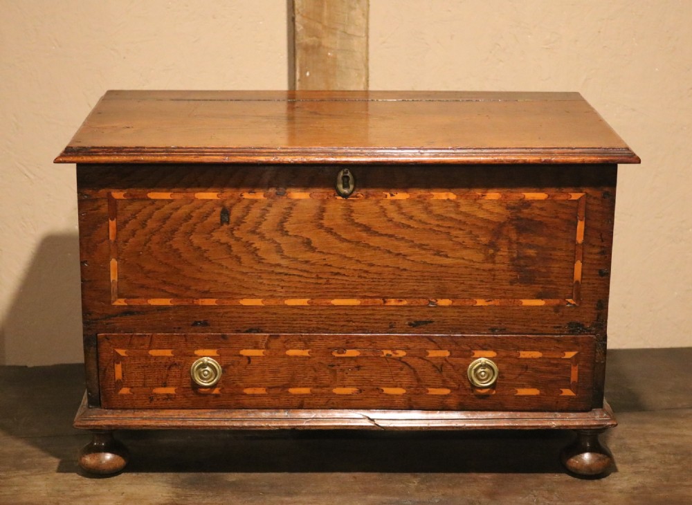 An 18th-century Welsh oak coffer bach featuring geometric inlay, a single lower drawer with brass handles, and turned bun feet. View II