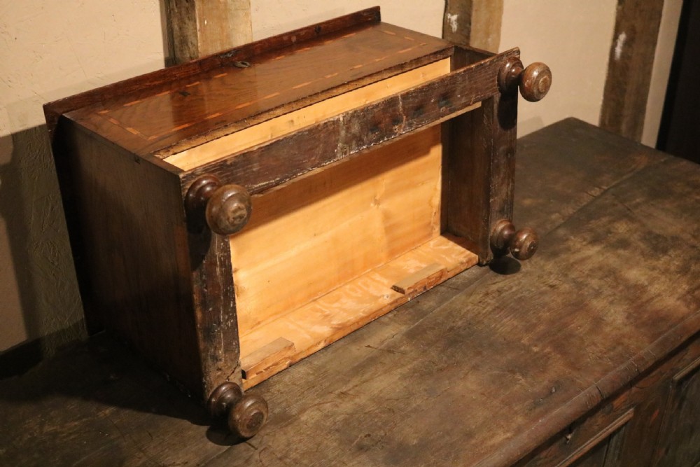 An 18th-century Welsh oak coffer bach featuring geometric inlay, a single lower drawer with brass handles, and turned bun feet. View VII
