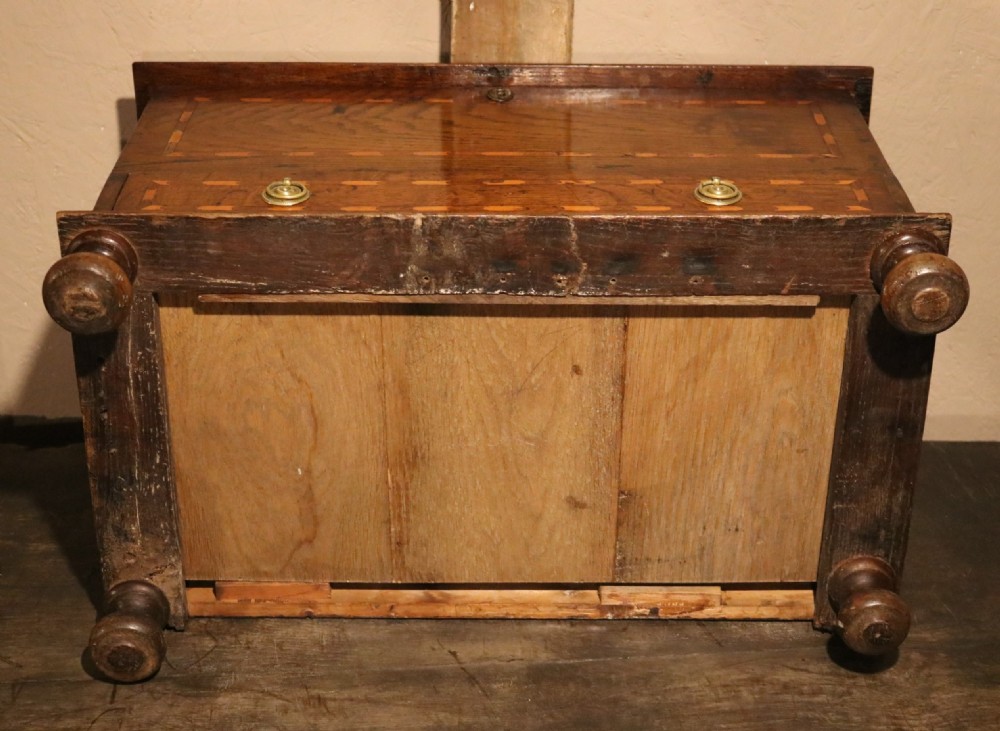 An 18th-century Welsh oak coffer bach featuring geometric inlay, a single lower drawer with brass handles, and turned bun feet. View VIII