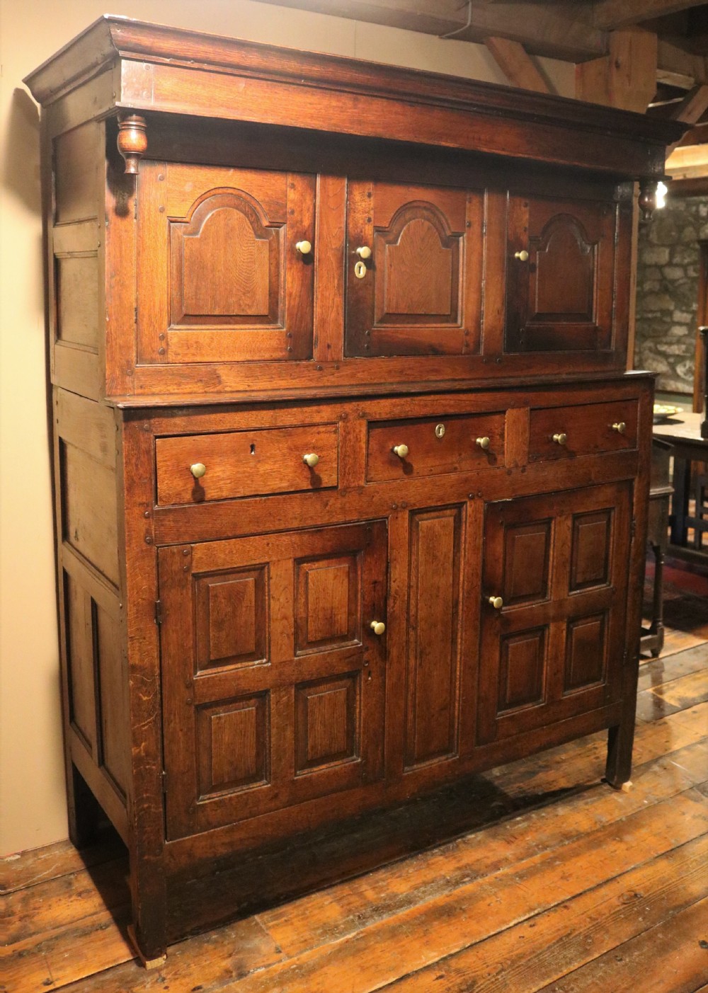 An eighteenth-century Welsh oak deuddarn two-part cupboard featuring a moulded cornice, three upper panelled doors with ogee arches, three mid drawers, and a lower cabinet with field panelled doors. View II