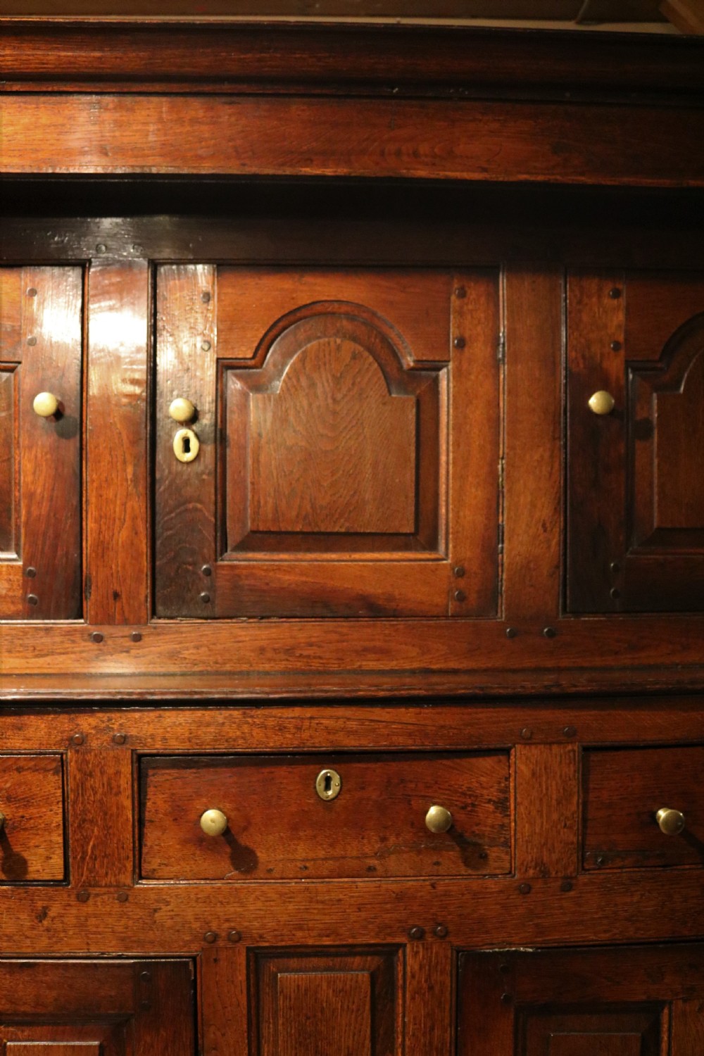 An eighteenth-century Welsh oak deuddarn two-part cupboard featuring a moulded cornice, three upper panelled doors with ogee arches, three mid drawers, and a lower cabinet with field panelled doors. View V