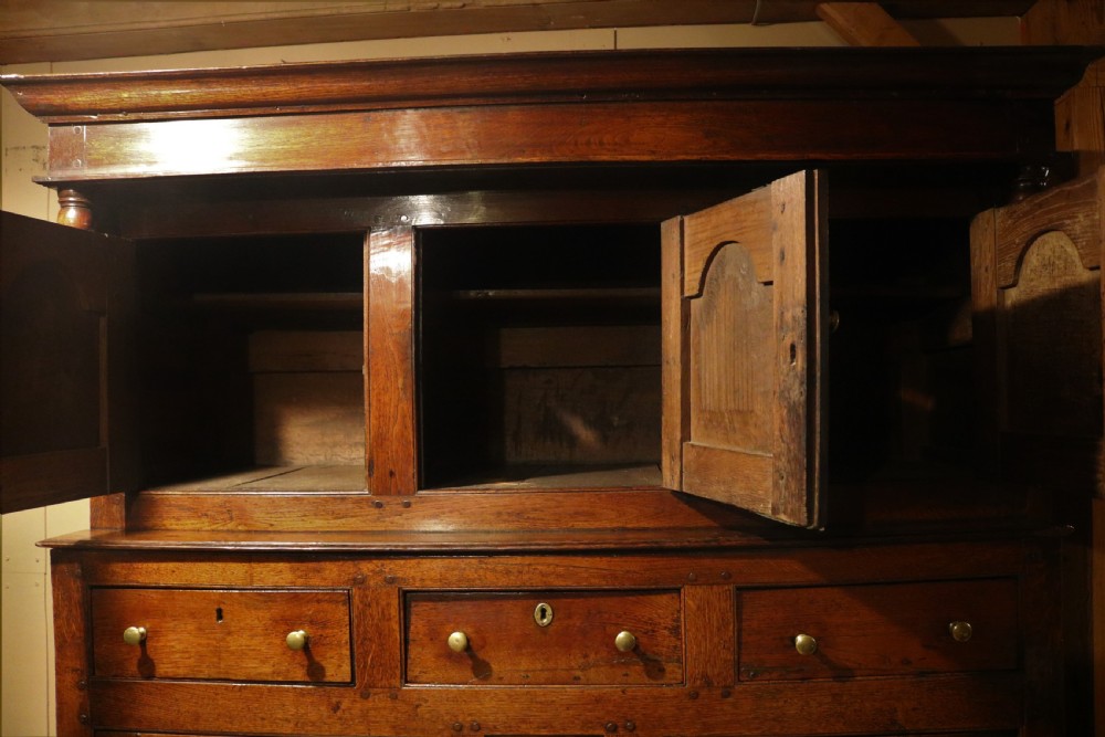 An eighteenth-century Welsh oak deuddarn two-part cupboard featuring a moulded cornice, three upper panelled doors with ogee arches, three mid drawers, and a lower cabinet with field panelled doors. View VIII