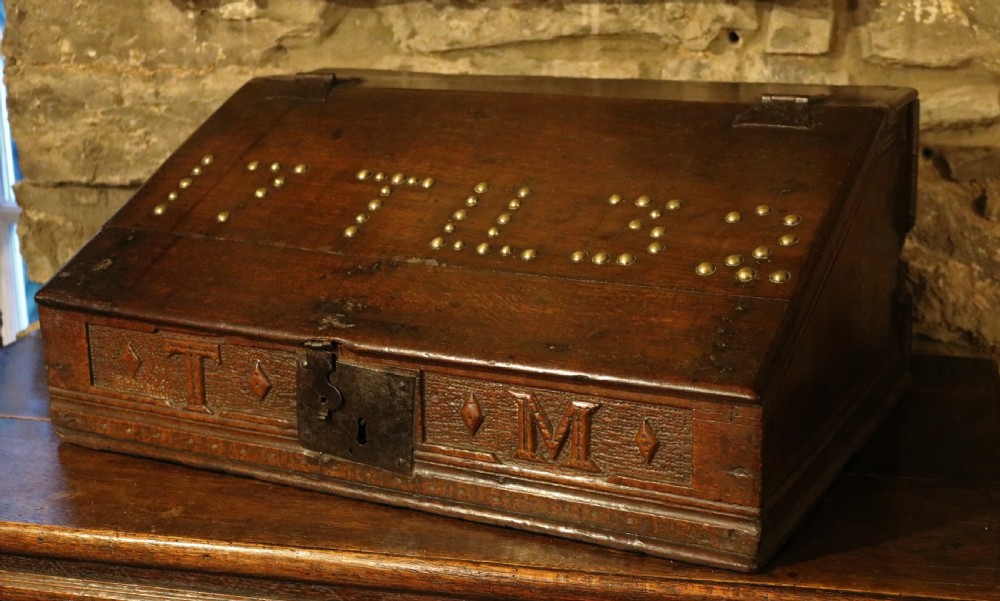 A dark oak sloped desk box featuring brass stud detailing with the year 1732, carved letters T M, and an iron lock plate. View II