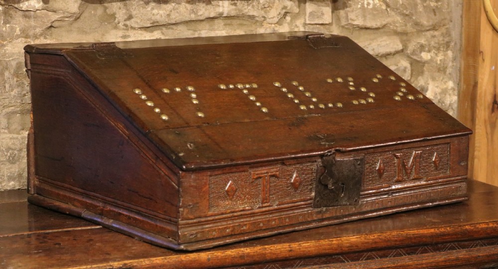 A dark oak sloped desk box featuring brass stud detailing with the year 1732, carved letters T M, and an iron lock plate. View III