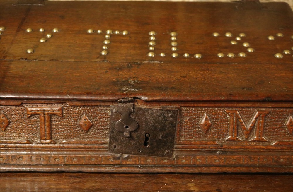 A dark oak sloped desk box featuring brass stud detailing with the year 1732, carved letters T M, and an iron lock plate. View IV