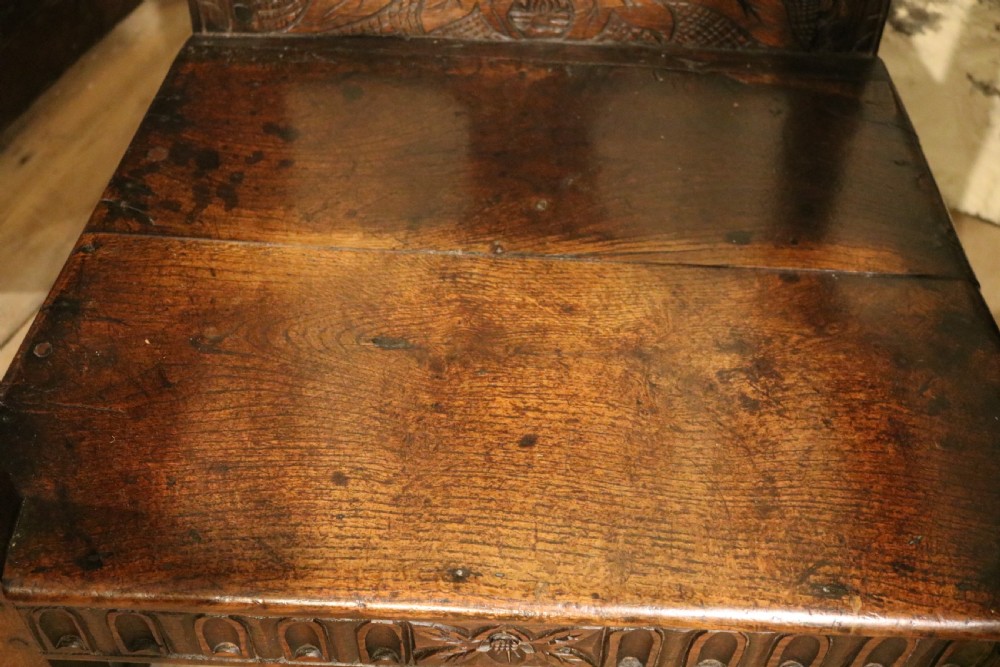 A dark carved oak Welsh armchair dating to the late 18th century with detailed foliate relief carving on the splat back and turned arm supports. View IX
