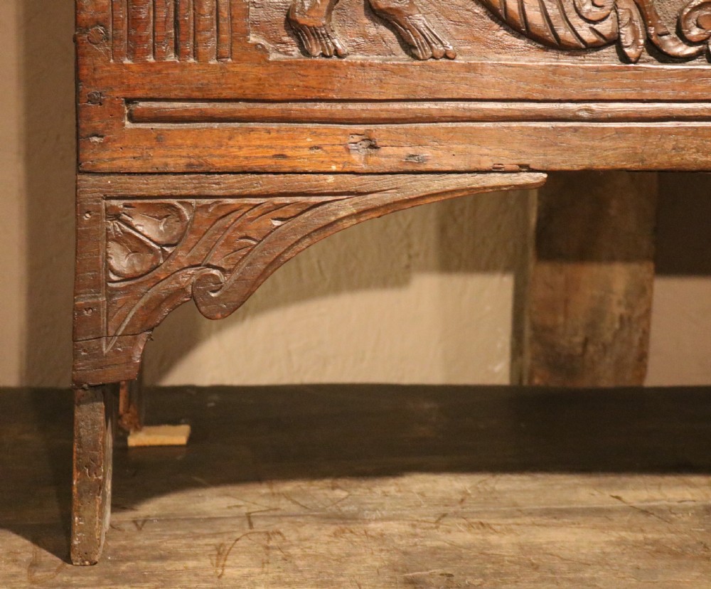 A dark brown carved oak chest featuring relief carvings of dragons, floral rosettes, and a central iron lock plate. View XI
