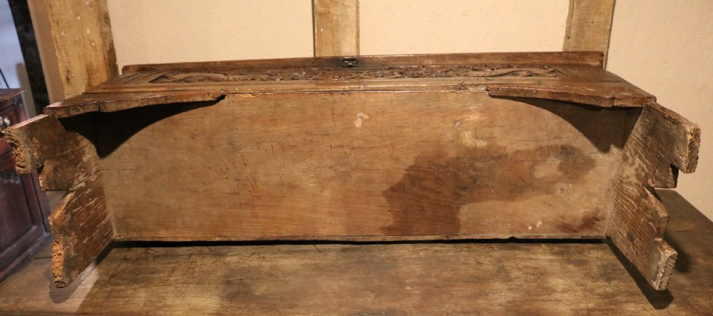 A dark brown carved oak chest featuring relief carvings of dragons, floral rosettes, and a central iron lock plate. View XVI